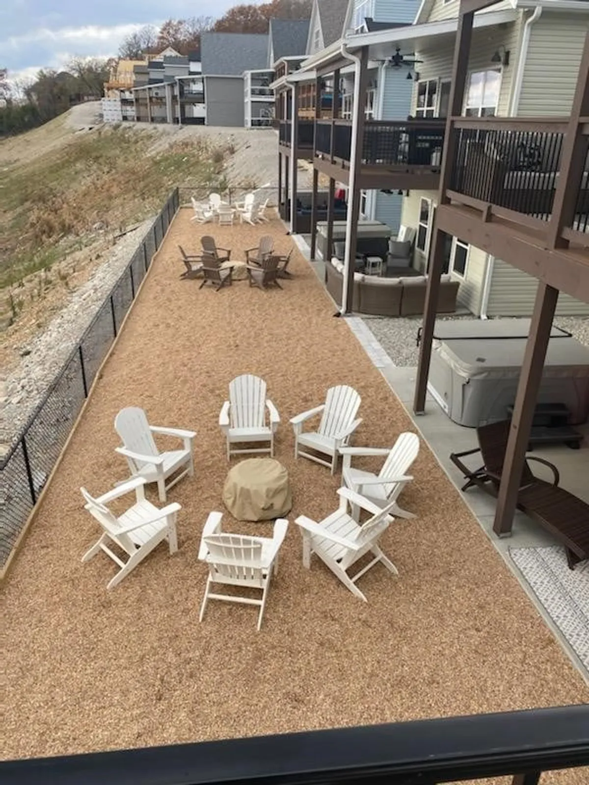 A cozy fire pit surrounded by white Adirondack chairs set on a landscaped gravel area, ideal for evening gatherings. The scene radiates comfort and togetherness as families and friends share stories or unwind under the open sky.