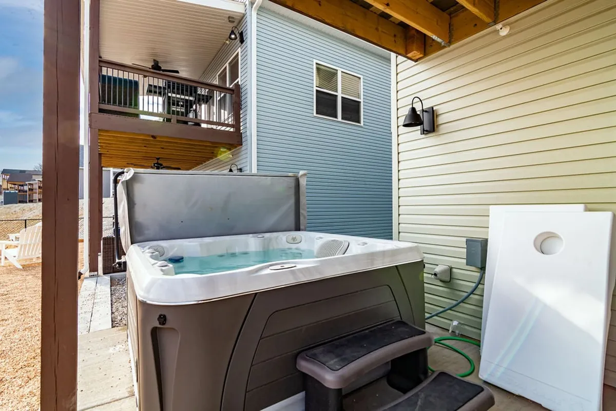 This image features a private hot tub set on a surrounding deck with exterior walls and ambient outdoor lighting, inviting relaxation and intimate social gatherings. The positioning suggests a tranquil escape with the possibility of enjoying nature and lake views directly from the tub.