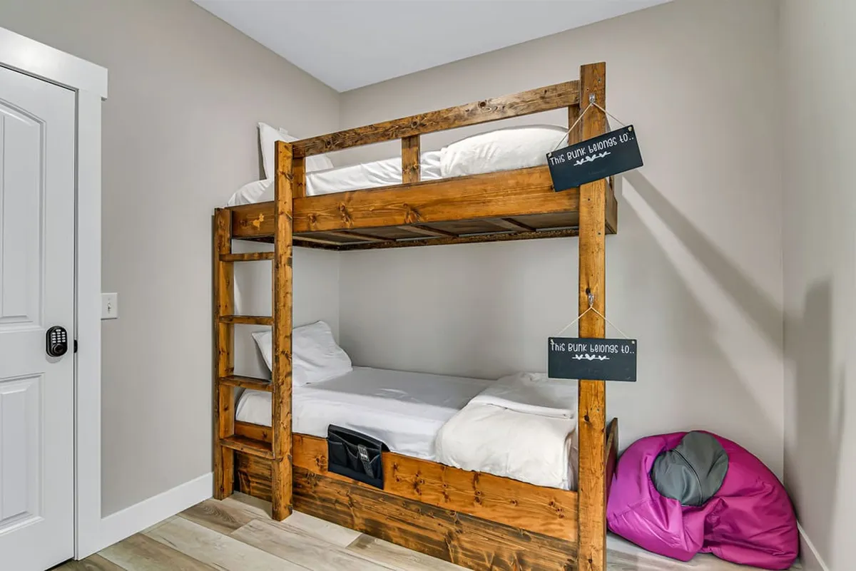 A cozy bunk room designed for kids, with a sturdy bunk bed, inviting bean bag chair, and bright white bedding. The setup radiates playful energy, offering a comfortable and cheerful retreat for young guests.